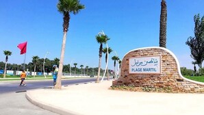 A sign for Plage Martil with a stone archway and palm trees in the background. - Residence Chems Corniche Martil 3915 (Martil)
