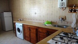 A kitchen with a washing machine, a stove, and a sink. - Residence Chems Corniche Martil 3915 (Martil)