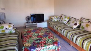 A bedroom with two beds, a TV, and a fan. - Residence Chems Corniche Martil 3915 (Martil)