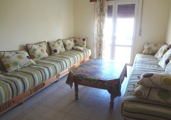 A room with two sofas, a wooden table, and a door with a view.
