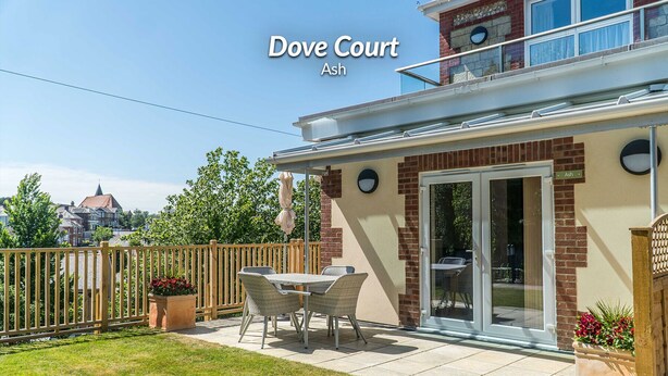 Una propiedad residencial llamada Dove Court Ash con un patio que cuenta con una mesa y sillas, una valla de madera y vistas a la ciudad.