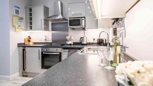 Una cocina moderna con electrodomésticos de acero inoxidable, encimera de granito y una botella de vino.