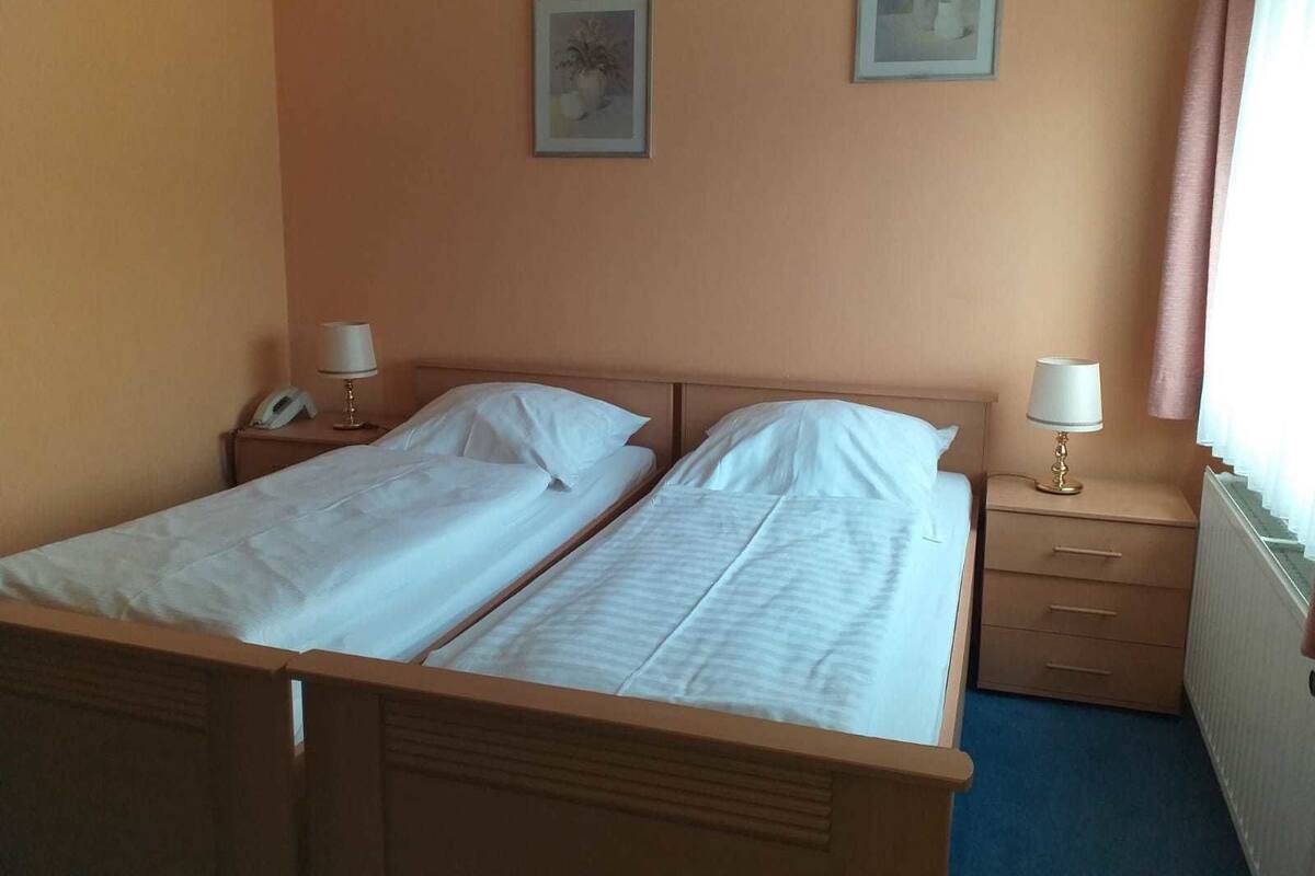 Ein Doppelbett mit zwei Nachttischen, jeder mit einer Lampe und einem Telefon.