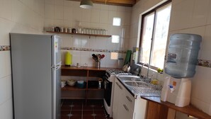 Una cocina compacta con refrigerador, estufa, lavamanos y dispensador de agua.