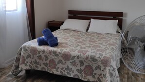 Una cama bien hecha con una colcha estampada con motivos florales, una toalla azul y un cabecero de madera.