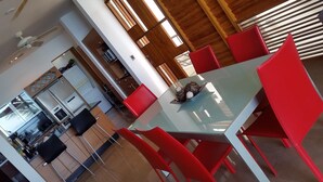 Un comedor moderno con una mesa de vidrio y sillas rojas.