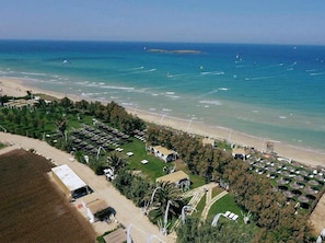 An aerial view of a beach resort with multiple bungalow-style accommodations, a sandy beach, and a clear view of the sea. - Fenced and heated pool, playground, bbq,3 patios, parking,14 km Nat. Reserve (San Vito Dei Normanni)