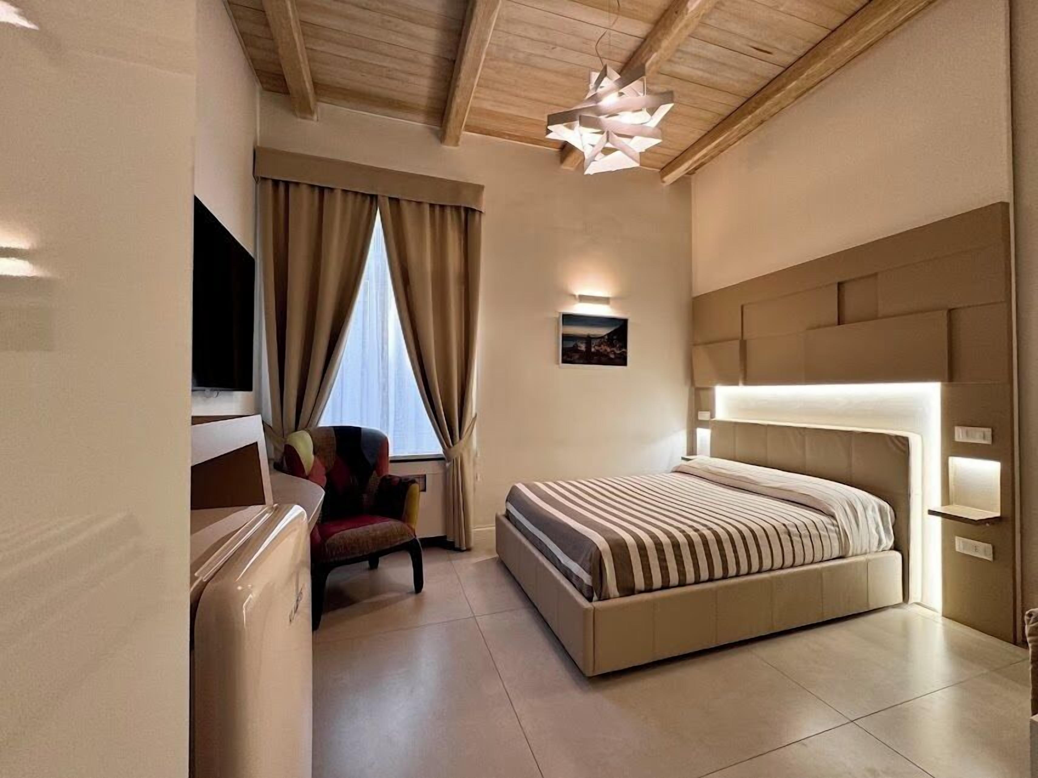 A modern hotel room with a large bed, a desk, a chair, and a television.