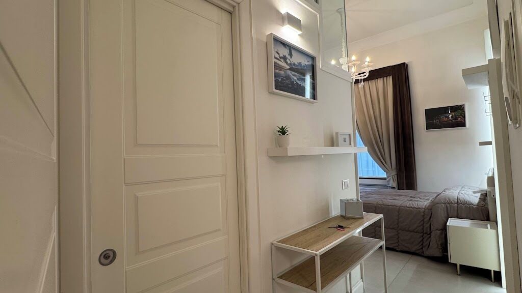 Une chambre à coucher comprenant un lit, des tables de chevet, un miroir et une étagère avec une plante.