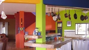 Une cuisine avec un comptoir en bois, des casseroles suspendues et une fenêtre donnant sur un beau paysage.