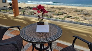 Une table de patio sur laquelle est posé un journal, donnant sur une plage avec des vagues et un ciel dégagé.