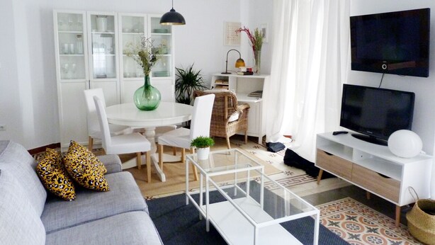 A modern living room with a sofa, coffee table, TV, dining area, and a bookshelf. - Very luminous apartment in the corner of the Cathedral, in the Arenal district (Sevilla)