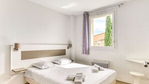 Un dormitorio moderno con una cama grande, una mesita de noche, una ventana con cortinas y un baño con lavamanos pedestal.