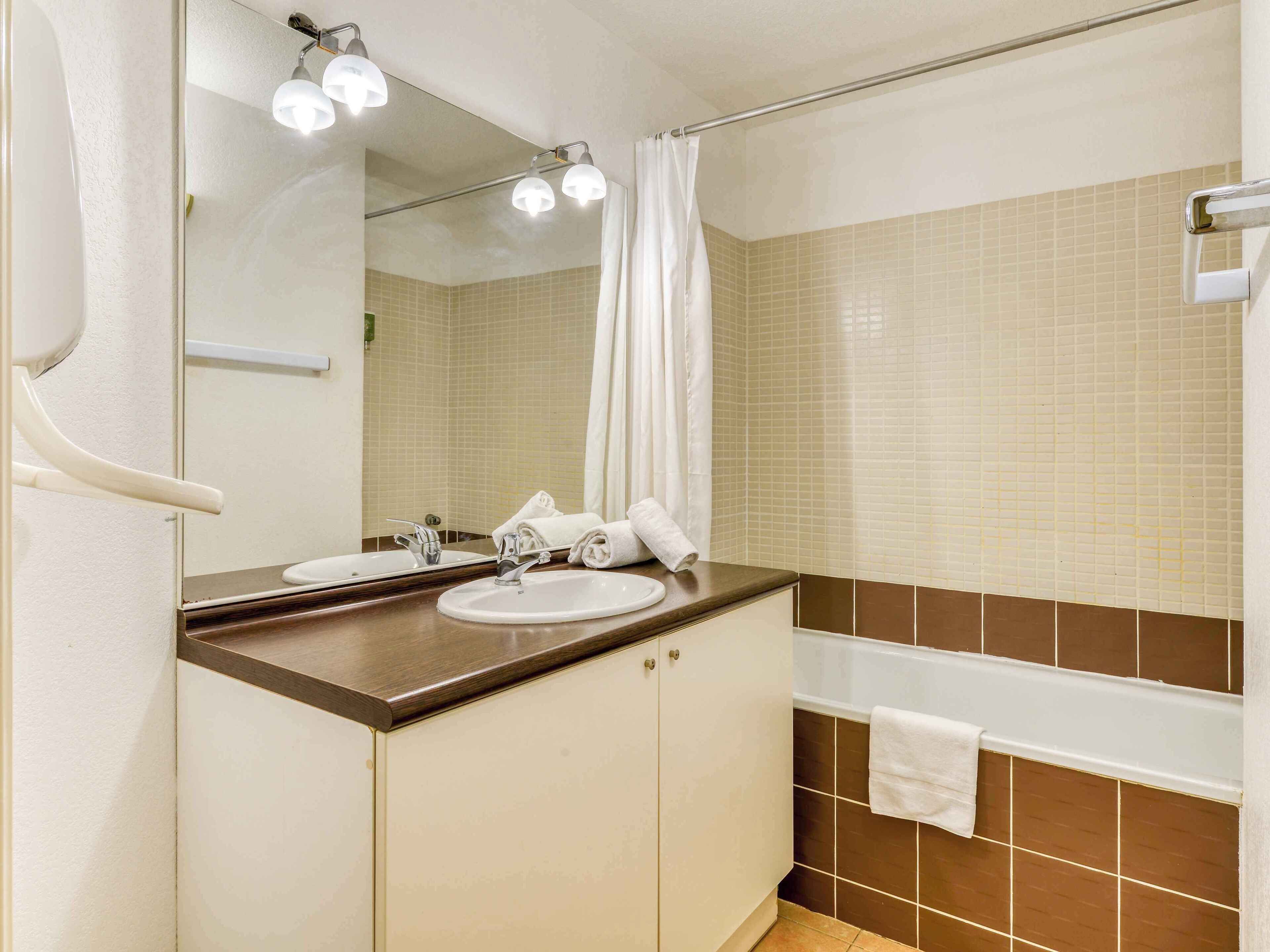 Een badkamer met een wastafel, spiegel en bad.