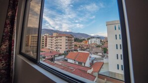 A view from a window overlooking a cityscape with buildings and mountains in the background. - Yellow Gem Apt - Campoverde (Cochabamba)