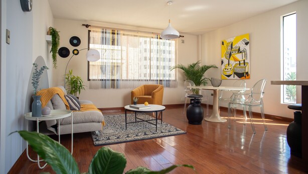 A modern living room with a sofa, armchair, coffee table, and dining area. - Yellow Gem Apt - Campoverde (Cochabamba)