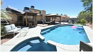 A backyard with a swimming pool, outdoor furniture, and a pergola.