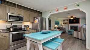 Een moderne keuken met roestvrijstalen apparatuur, een blauwe houten tafel en een gezellig woongedeelte met een open haard.
