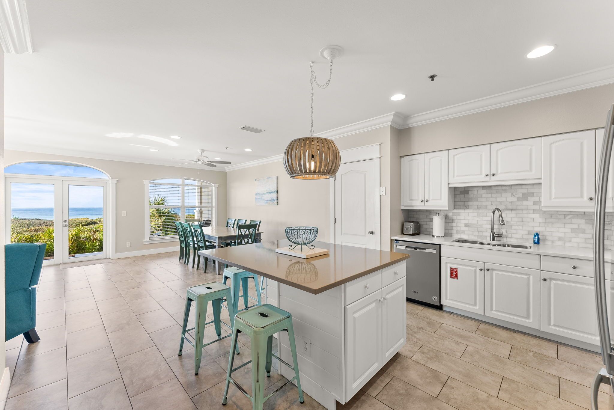 A spacious kitchen with a large island, white cabinetry, and a view to the outside.