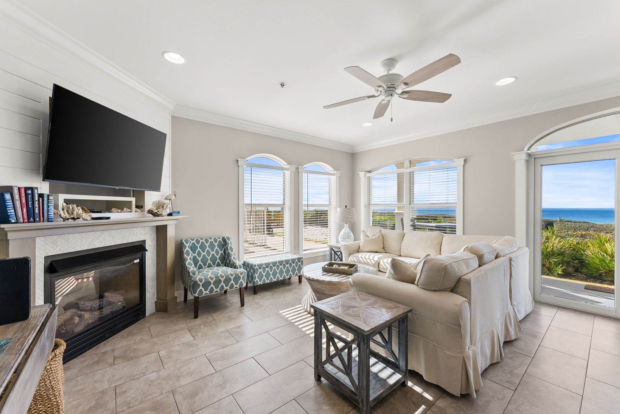 A living room with a fireplace, television, sofa, and large windows with a view.