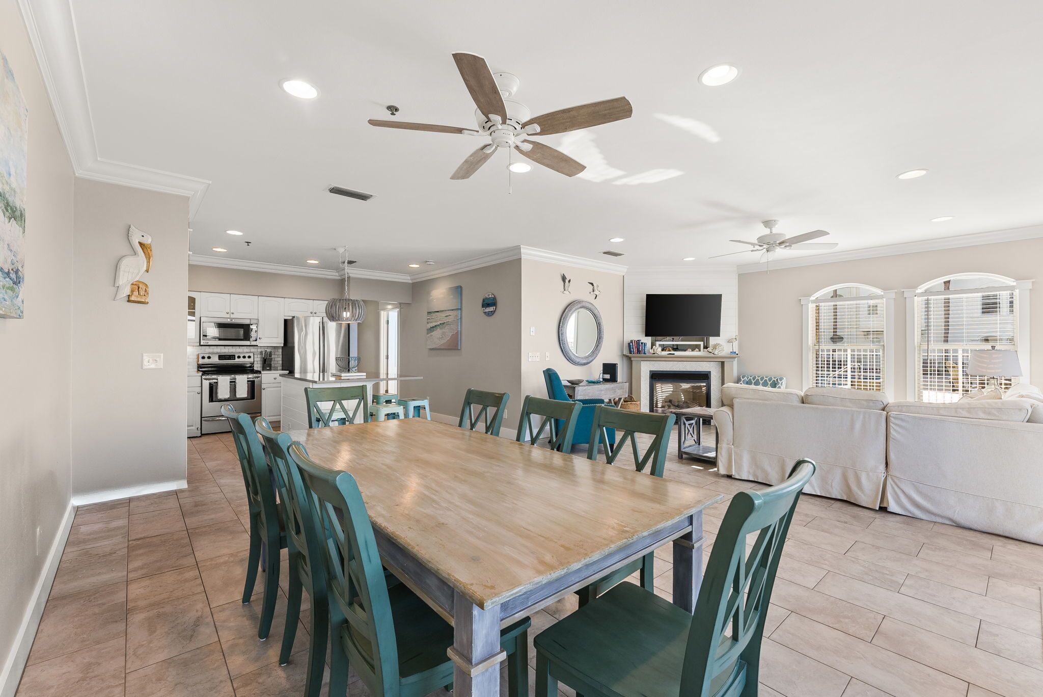 A spacious kitchen with modern appliances, a dining area with a wooden table and chairs, and a living area with a sofa and fireplace.