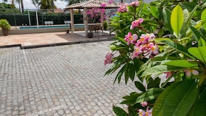 A paved patio area with a pool, a gazebo, and lush greenery. - Maria Quitéria Hotel e Flat (Feira de Santana)
