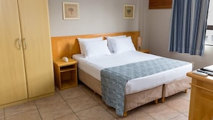 A hotel room with a bed, nightstand, wooden wardrobe, and an air conditioning unit. - Maria Quitéria Hotel e Flat (Feira de Santana)