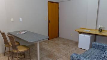A small room with a table, two chairs, a refrigerator, and a door.