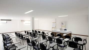 A conference room with rows of chairs and tables, a whiteboard, and a laptop on a table.