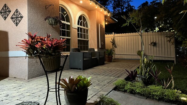 A patio area with a covered seating area, potted plants, and a wooden fence.