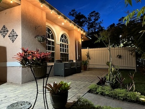 A patio area with a covered seating area, potted plants, and a wooden fence.