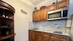A kitchen with wooden cabinets, a stainless steel microwave, and a marble backsplash.