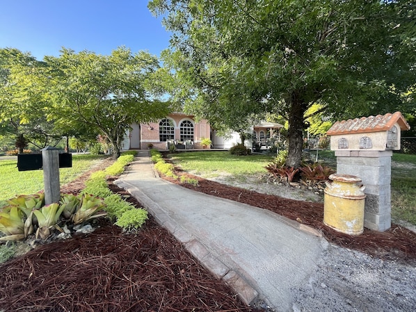 A pathway leading to a building with a garden and a mailbox.