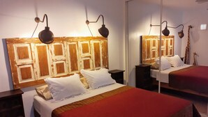 Een slaapkamer met twee bedden, houten hoofdeinden, nachtkastjes en wandlampen.