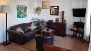 Een woonkamer met een bank, salontafel, televisie en decoratieve objecten.