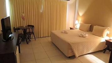 A hotel room with a bed, a desk with a chair, a television, and curtains.