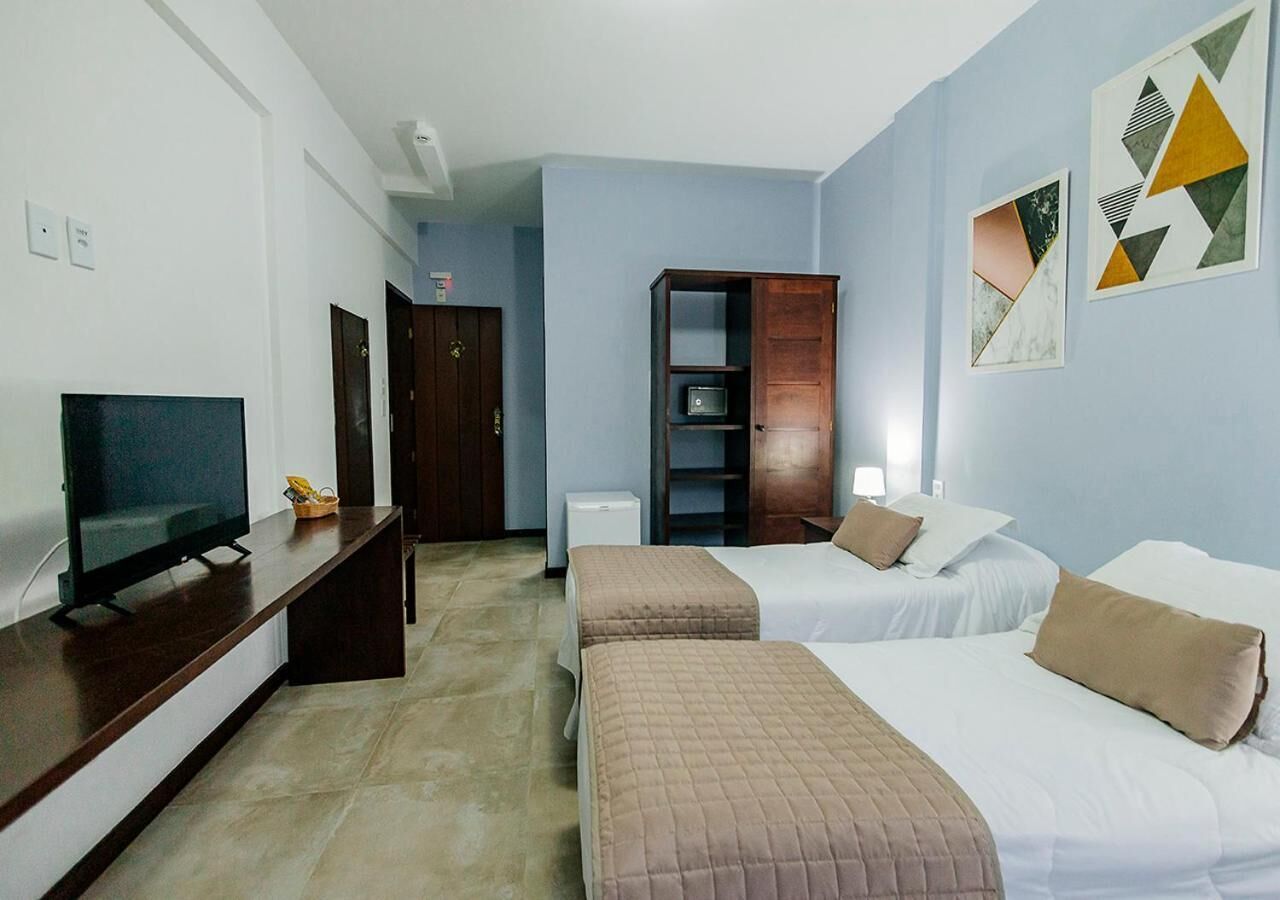 A hotel room with two beds, a TV, a desk, and a wardrobe.