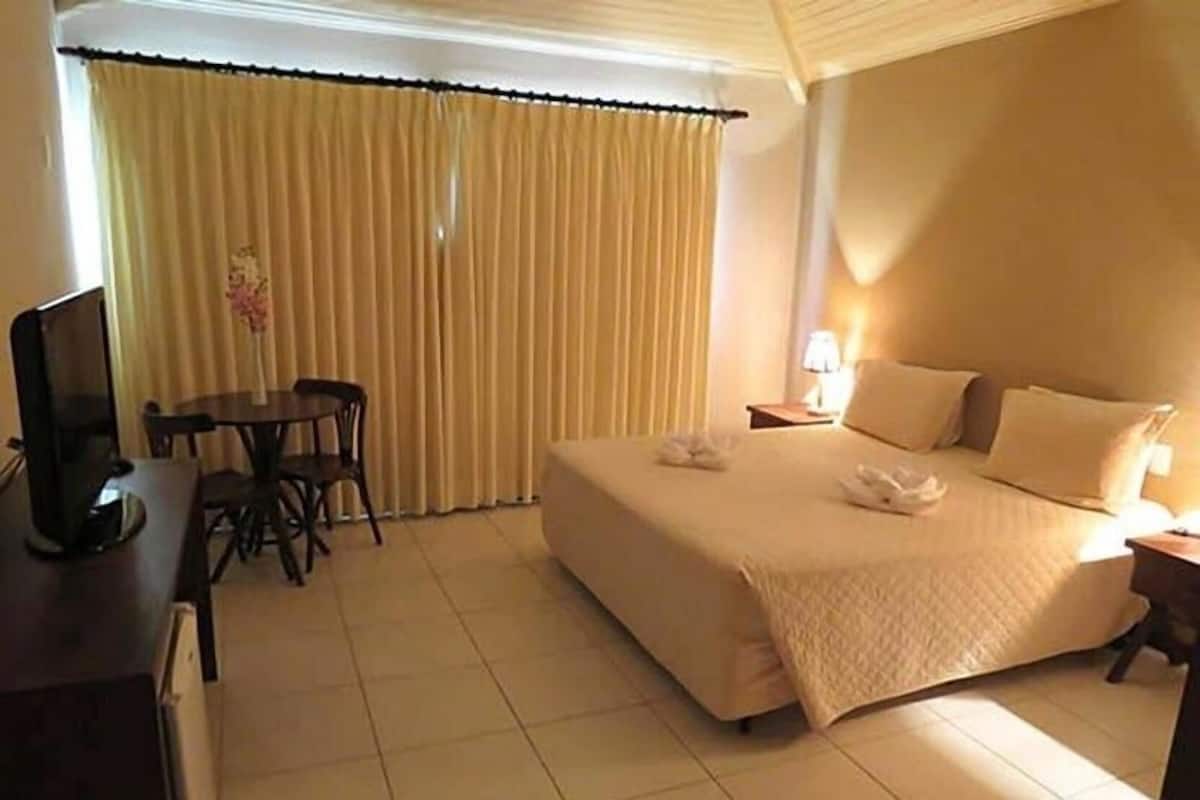 A hotel room with a bed, a desk, a chair, and a television.