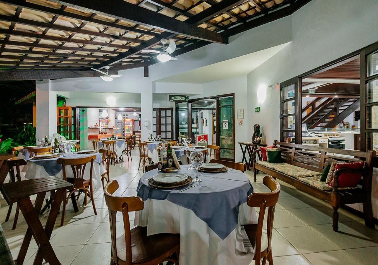 A restaurant with round tables, wooden chairs, and a ceiling with wooden beams.