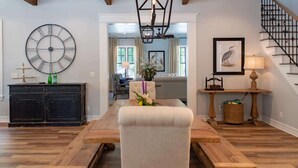 Ein geräumiges Wohnzimmer mit einem Holzessttisch, einer großen Wanduhr und einer Treppe.