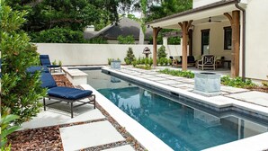 Ein Swimmingpool mit Liegestühlen, einer Pergola und einer Terrasse mit Gartenmöbeln.