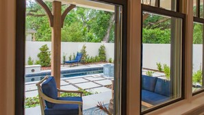 Eine Terrasse mit Pool, blauen Stühlen und einer weißen Wand.
