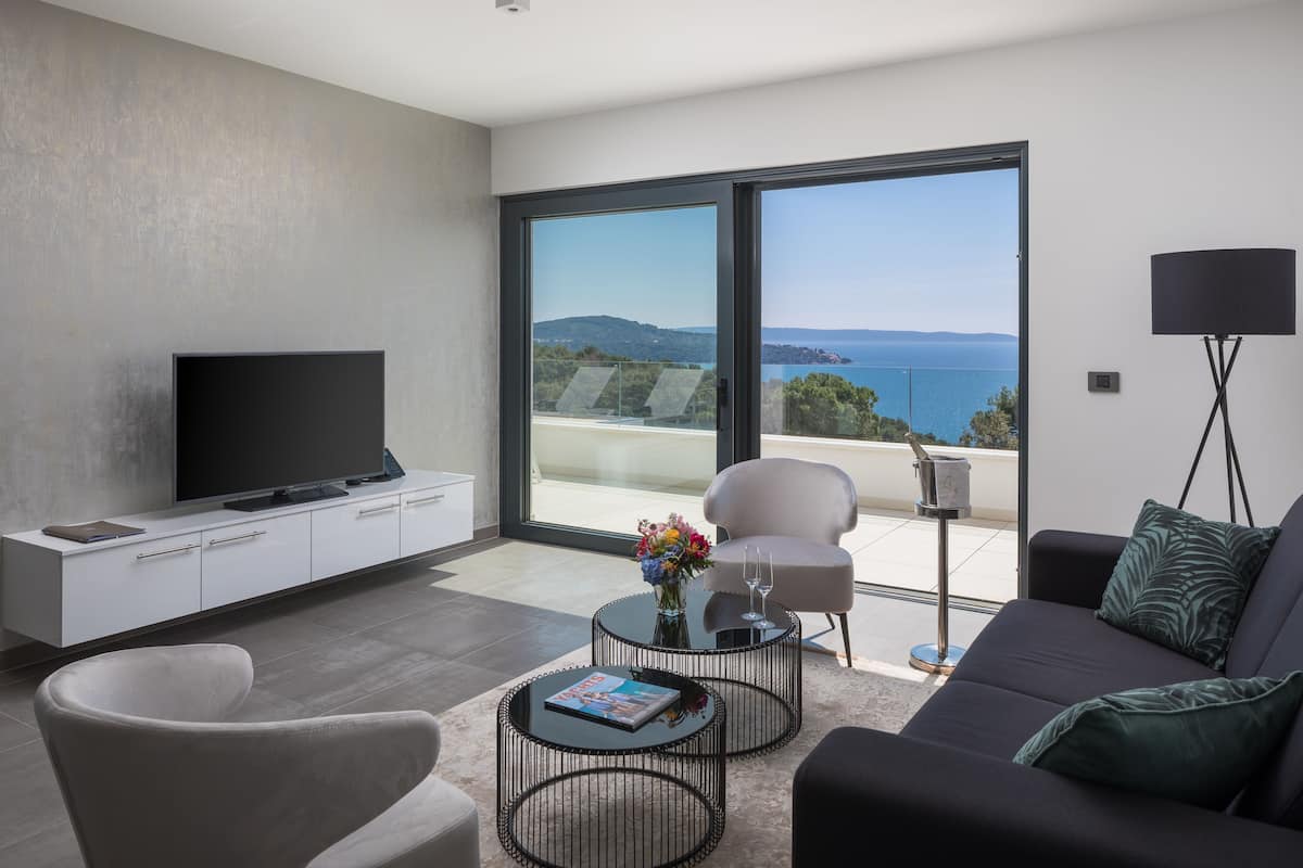Una sala de estar moderna con televisor de pantalla plana, un sofá, una mesa de centro y un balcón con vista al mar.
