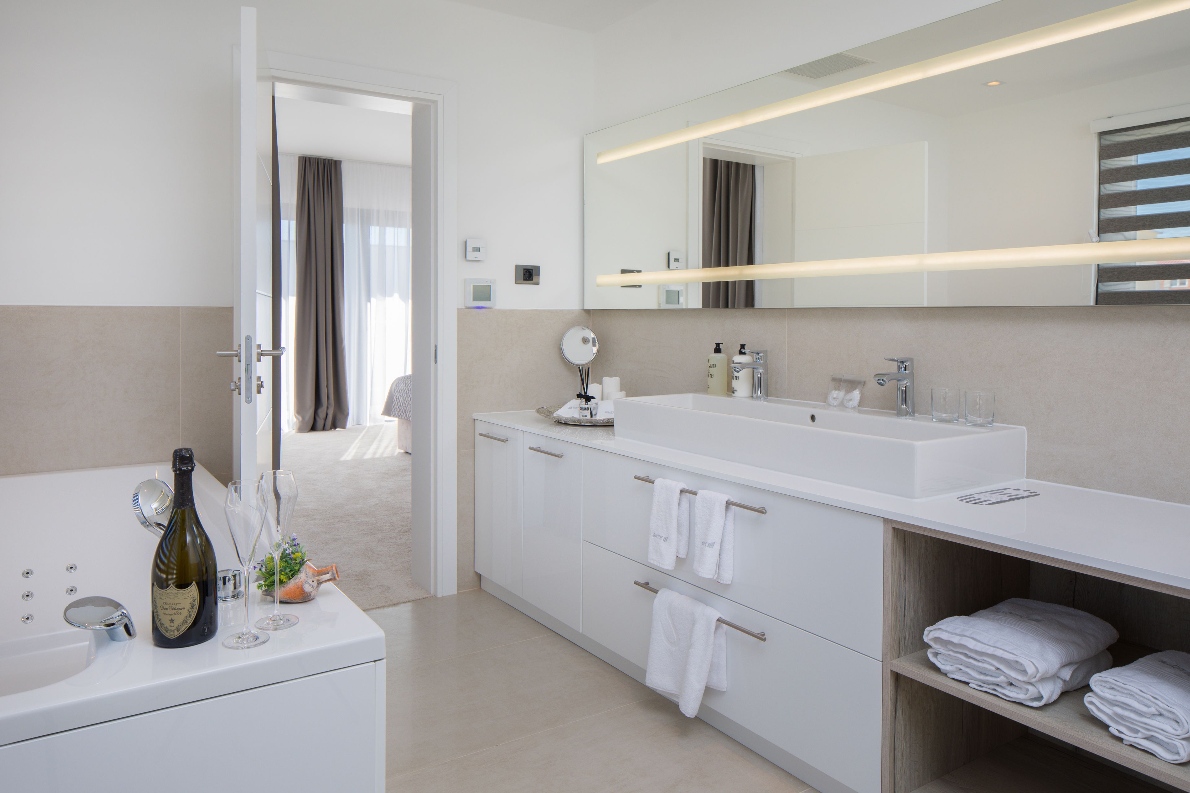 A modern bathroom with a large sink, mirror, and towel rack.