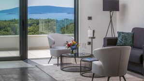 A modern living room with a view of the sea, a sofa, a chair, a coffee table, and a floor lamp. - Villas Baotic (Seget)