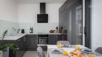 Eine moderne Küche mit dunklen Schränken, einem eingebauten Backofen und einem großen Fenster.