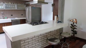 Eine moderne Küche mit Kochinsel, Edelstahlgeräten und einer Wand mit Ziegeln.