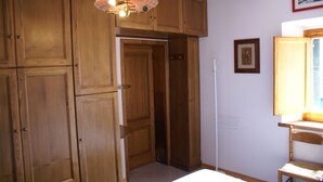 Un dormitorio con armarios de madera, una cama, una silla y una ventana con vistas.