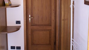 Una puerta de madera con manija, flanqueada por armarios de madera y una pared blanca.