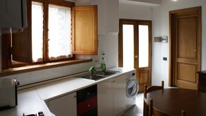 Una cocina compacta con lavadora integrada, un lavamanos y armarios de madera.